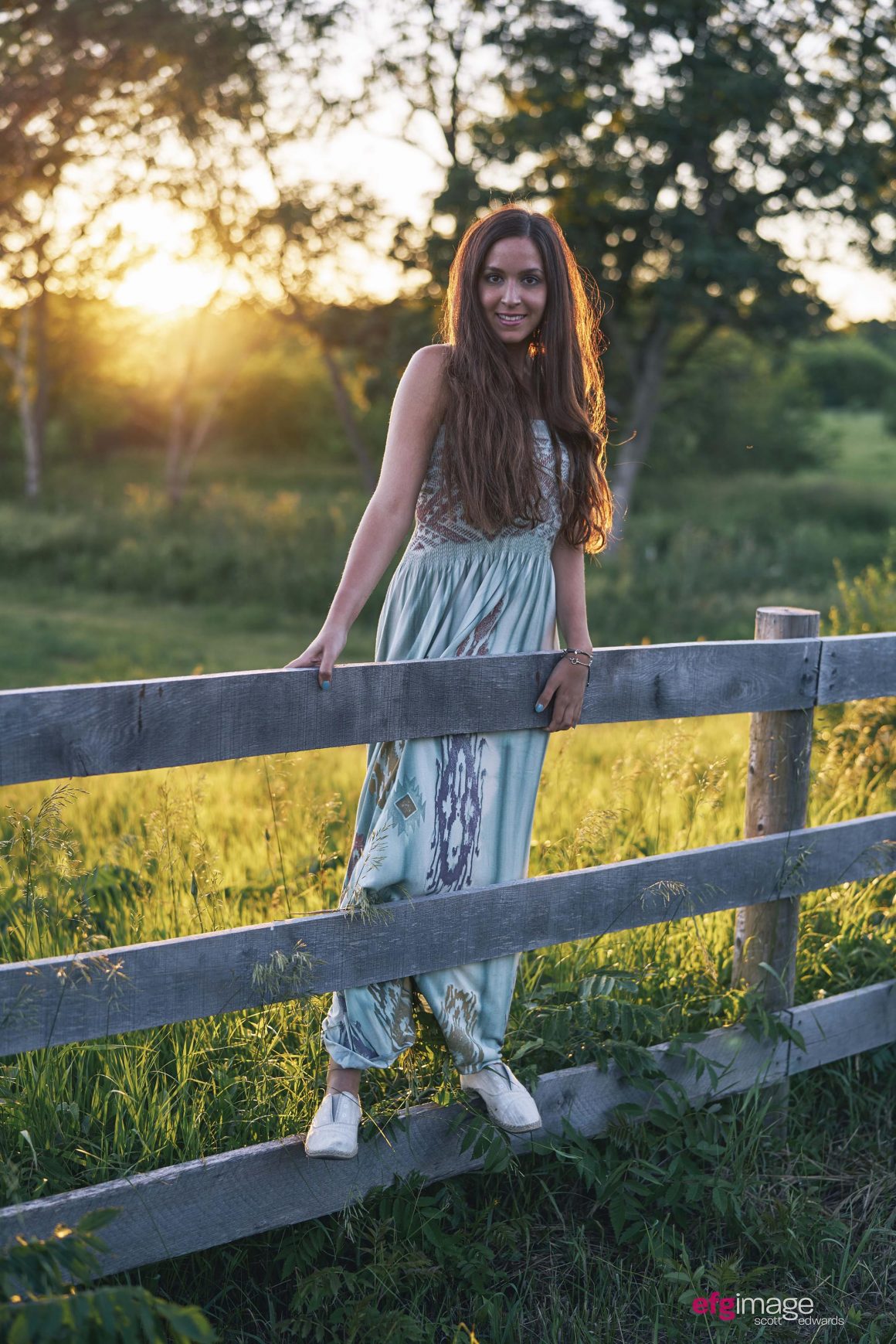 beautiful girl on fence at sunset